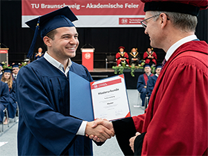 Glücklicher Absolvent nimmt Masterzeugnis entgegen-1